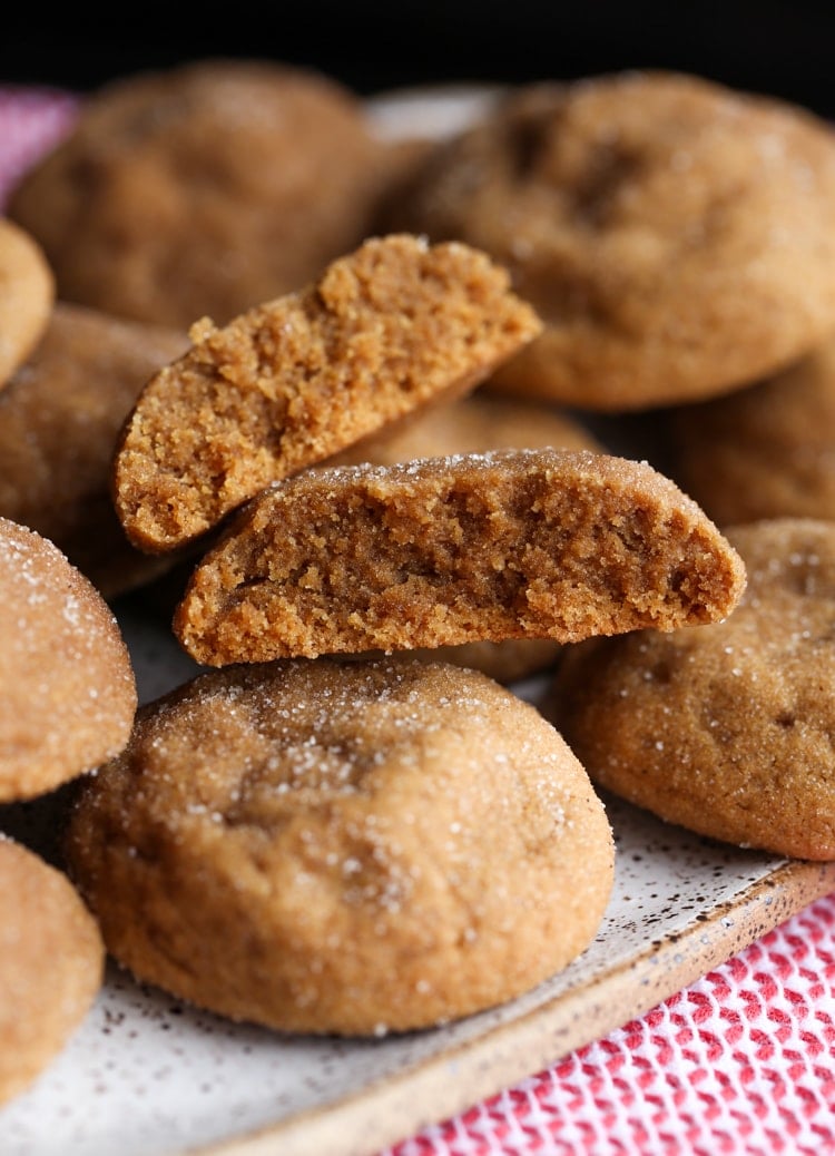 Gingerdoodles suaves apilados en un plato, con una galleta partida por la mitad.