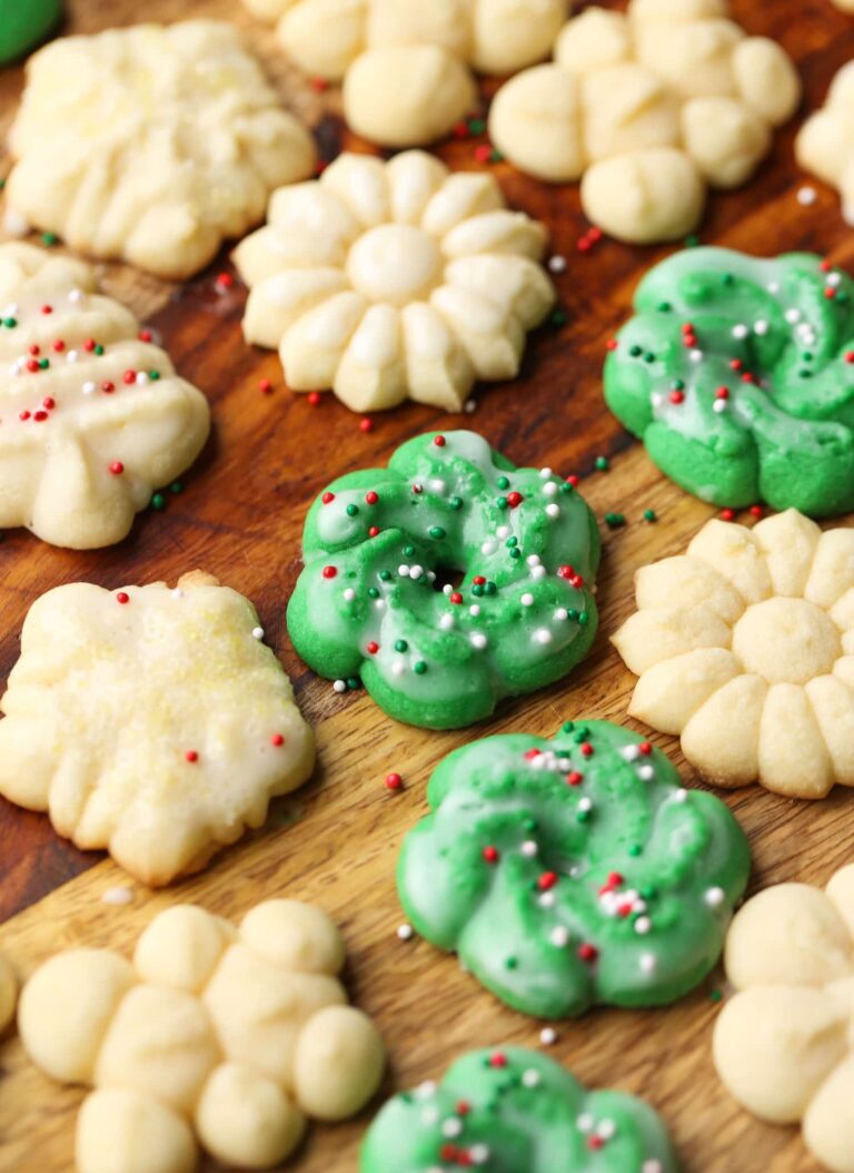 Perfect Spritz Cookies en varias formas y colores dispuestas sobre una encimera de madera.