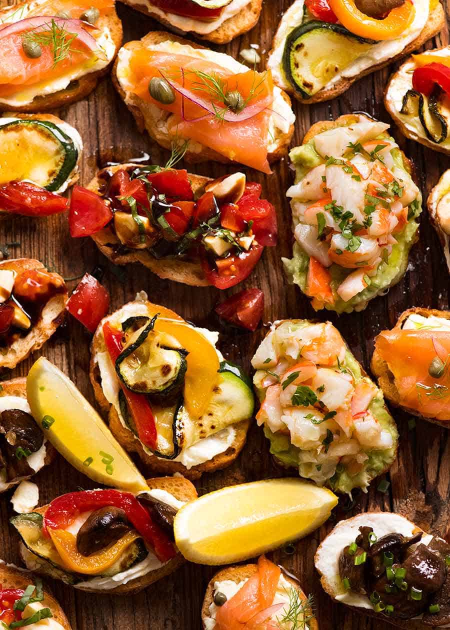 Tabla de madera rellena de Crostini - Salmón Ahumado, Gamba Aguacate, Mediterráneo y Caprese