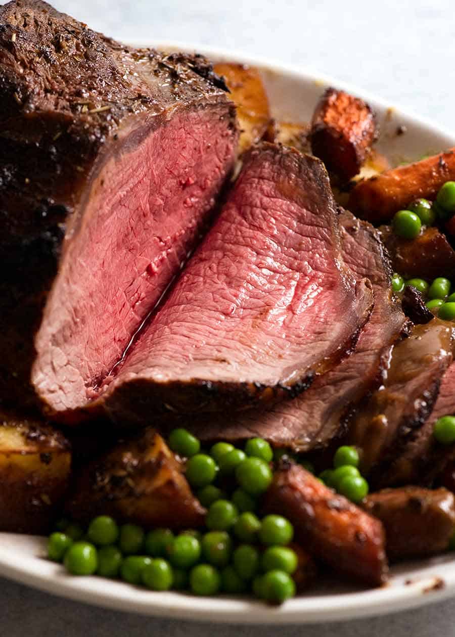 Rodajas de Roast Beef Marinado en un plato con verduras asadas, listo para servir
