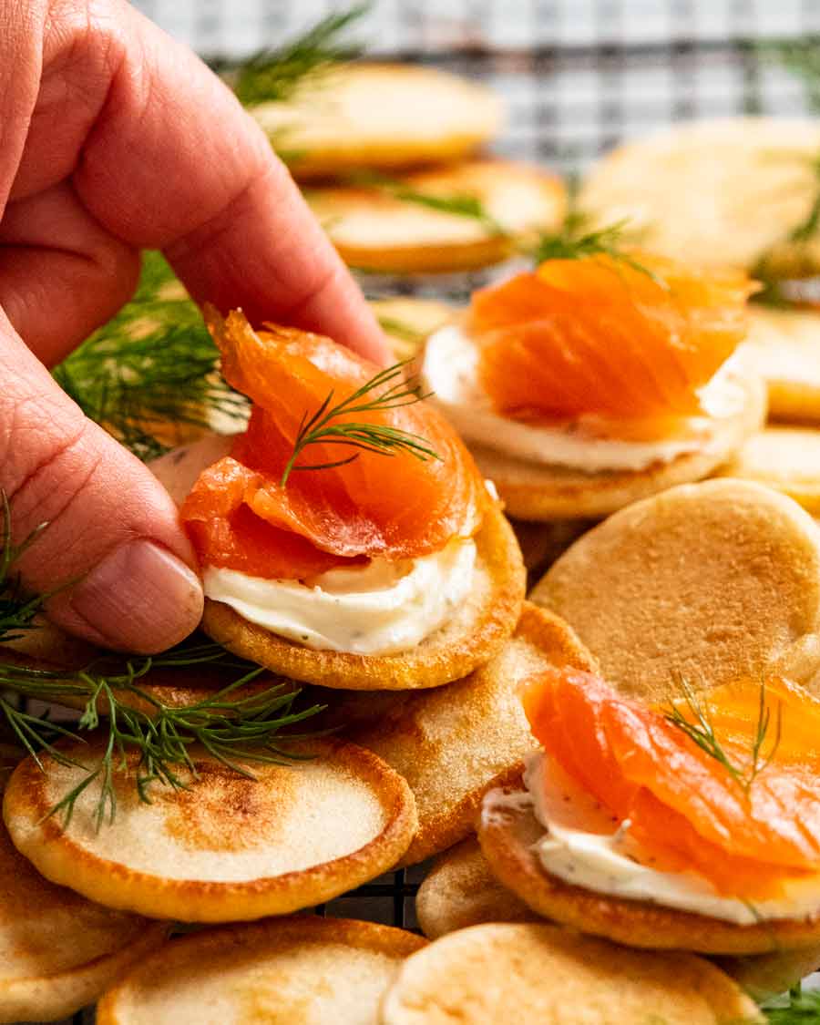Mano recogiendo Blini con salmón ahumado