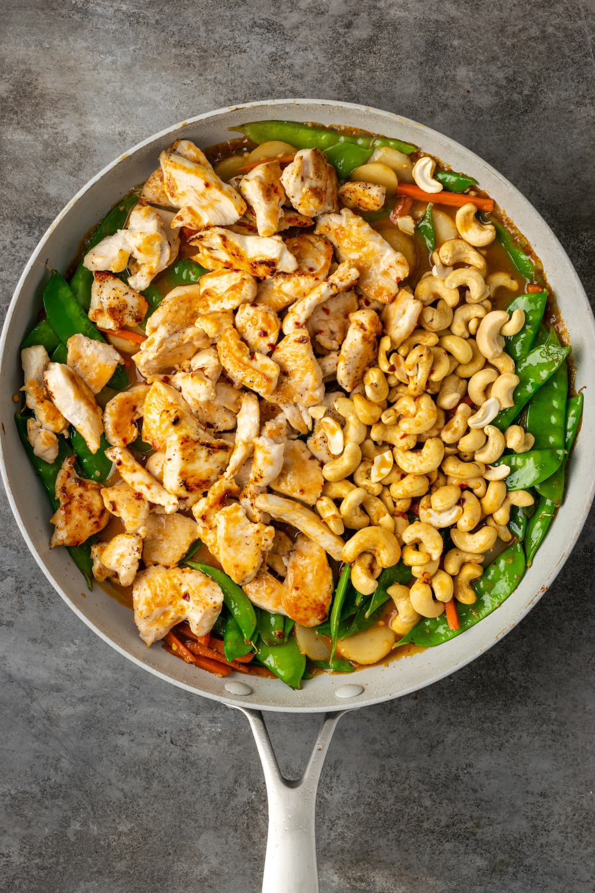 ¡Este pollo con anacardos de 25 minutos es una alternativa fácil a la comida para llevar! Hecho de jugoso pollo cocinado con verduras en una sabrosa salsa salteada. Pollo dorado y anacardos agregados a una sartén con verduras salteadas.