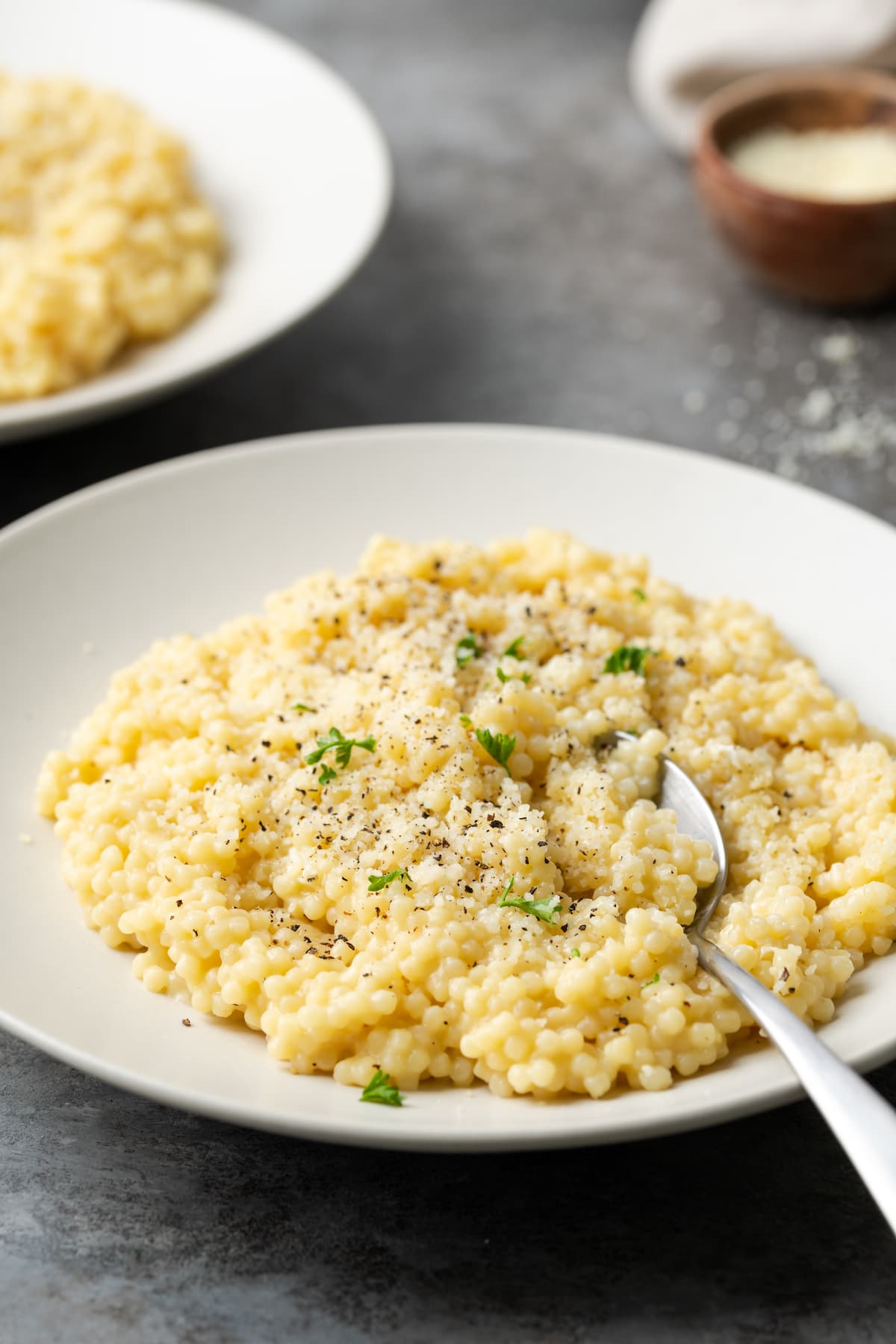 Pastina servida en un plato blanco cubierta con pimienta negra y queso parmesano.