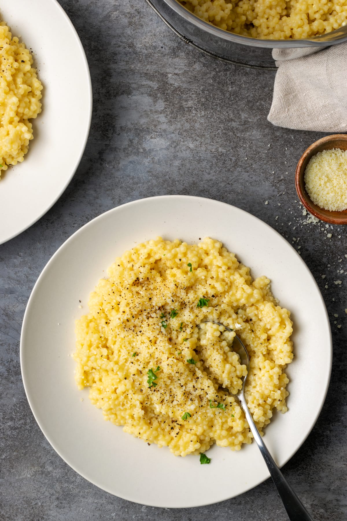 Vista aérea de la pastina servida en un plato blanco cubierto con pimienta negra y queso parmesano.