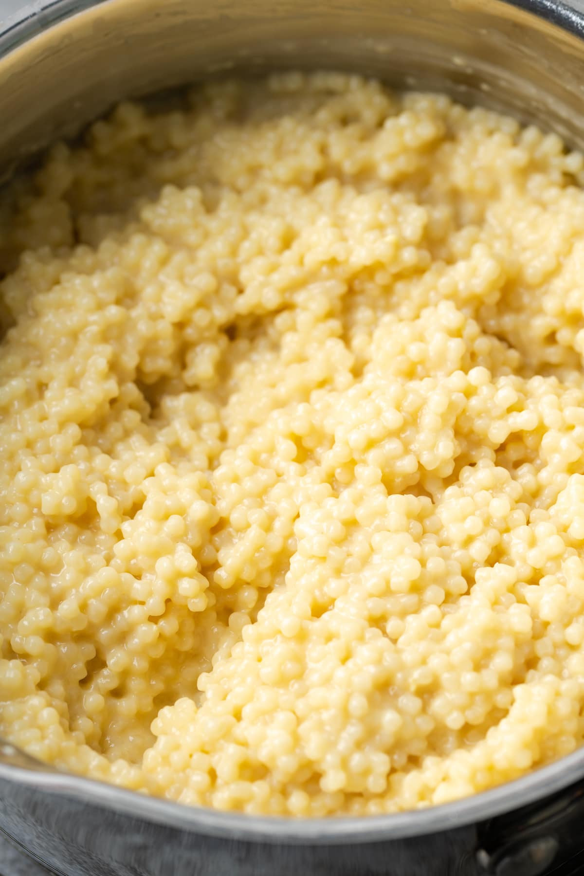 Primer plano de pasta pastina cremosa dentro de una olla.