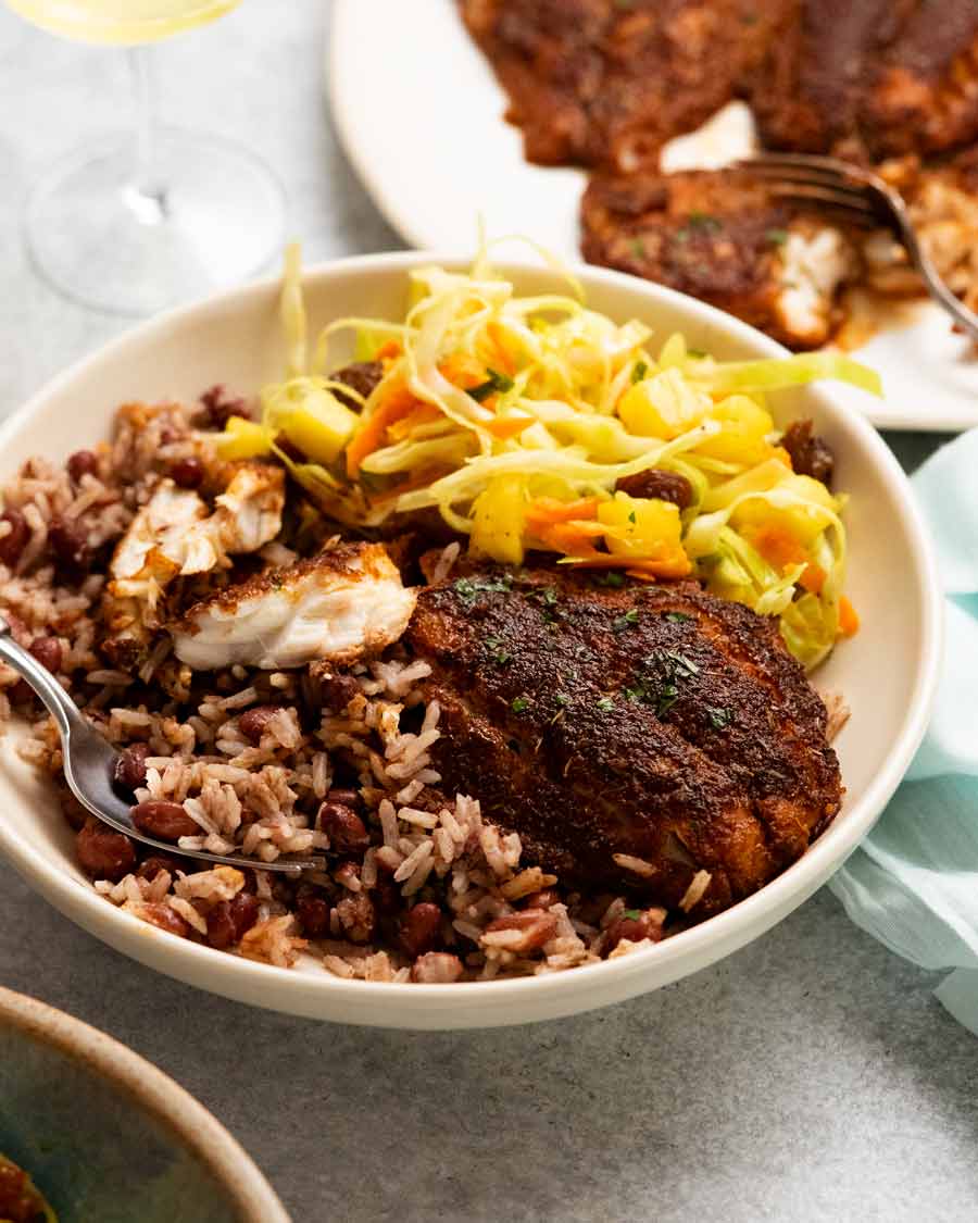 Jerk Fish jamaicano en un plato con ensalada jamaicana y arroz con coco y frijoles