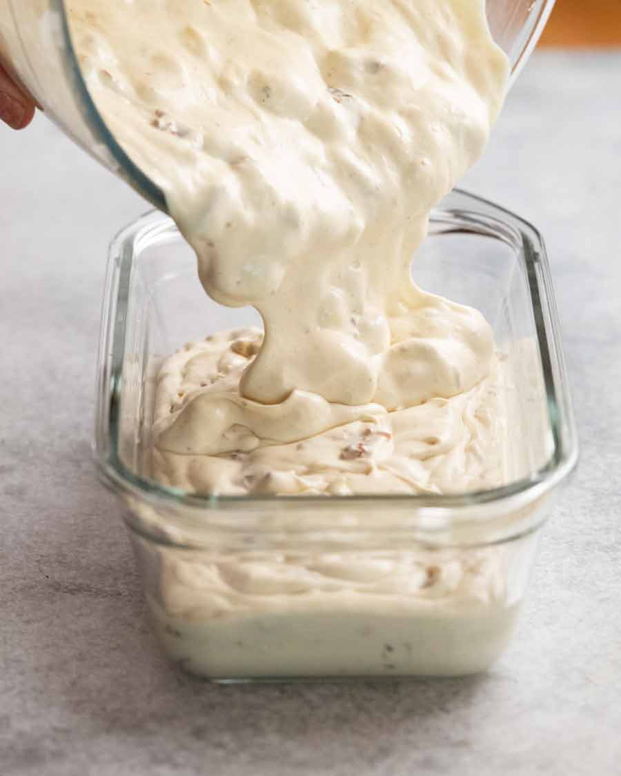 Verter helado de ron con pasas en un recipiente para helados