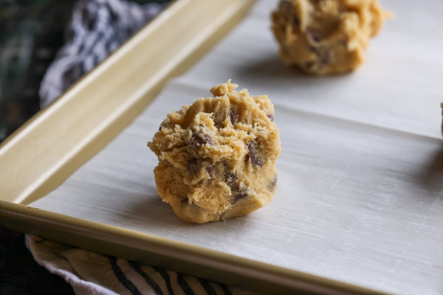 ¡Estoy seguro de que esta es la MEJOR receta de imitación para la galleta Crumbl con chispas de chocolate! ¡Espeso, mantecoso, suave y cargado de chispas de chocolate con leche! Cuchara de masa para galletas en una bandeja para hornear