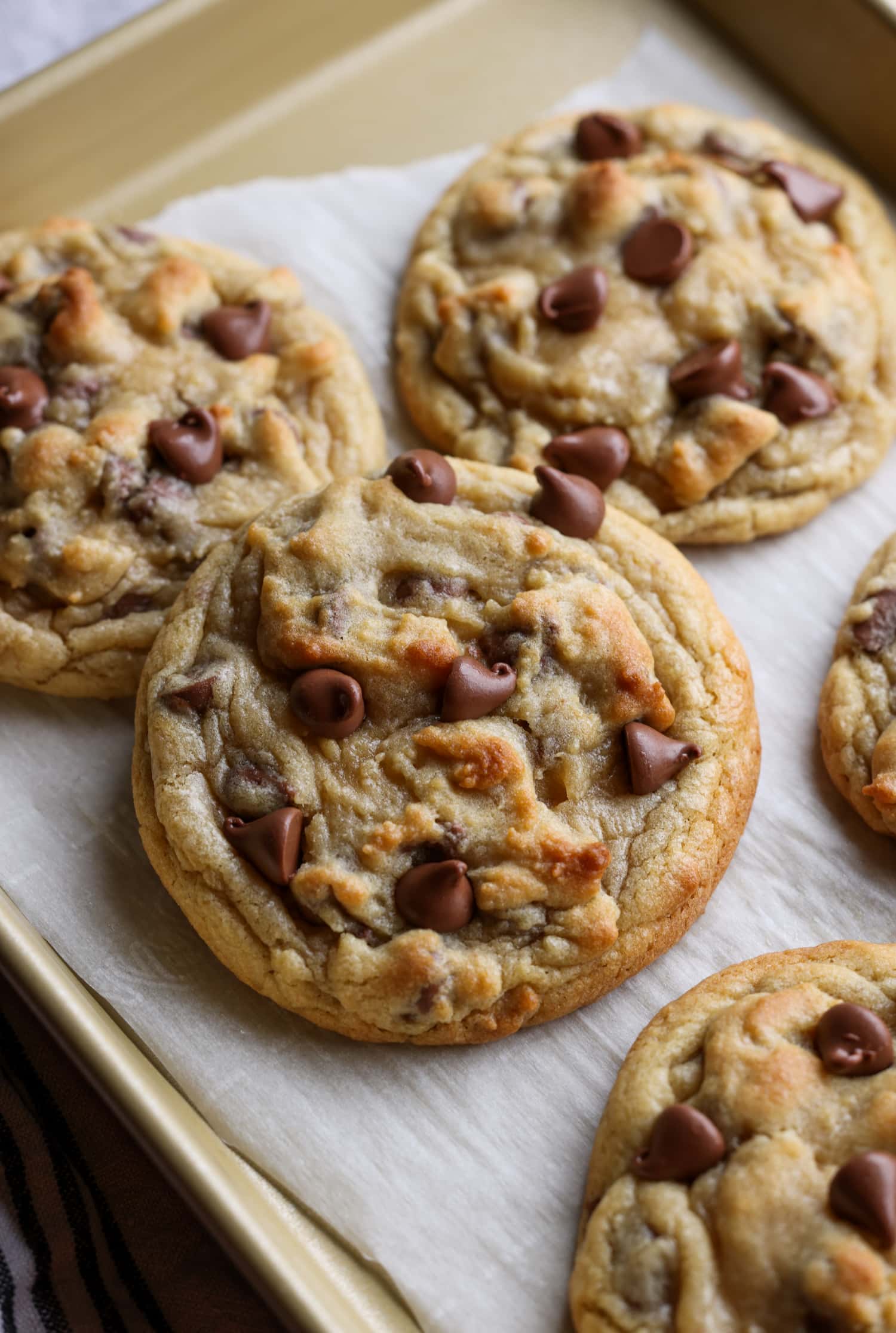 ¡Estoy seguro de que esta es la MEJOR receta de imitación para la galleta Crumbl con chispas de chocolate! ¡Espeso, mantecoso, suave y cargado de chispas de chocolate con leche! Copycat Crumbl Cookie en una bandeja para hornear galletas