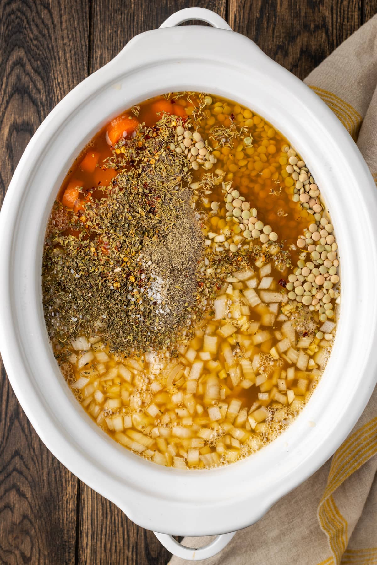 Ingredientes para la sopa de lentejas ensamblados en el recipiente de una olla de barro.