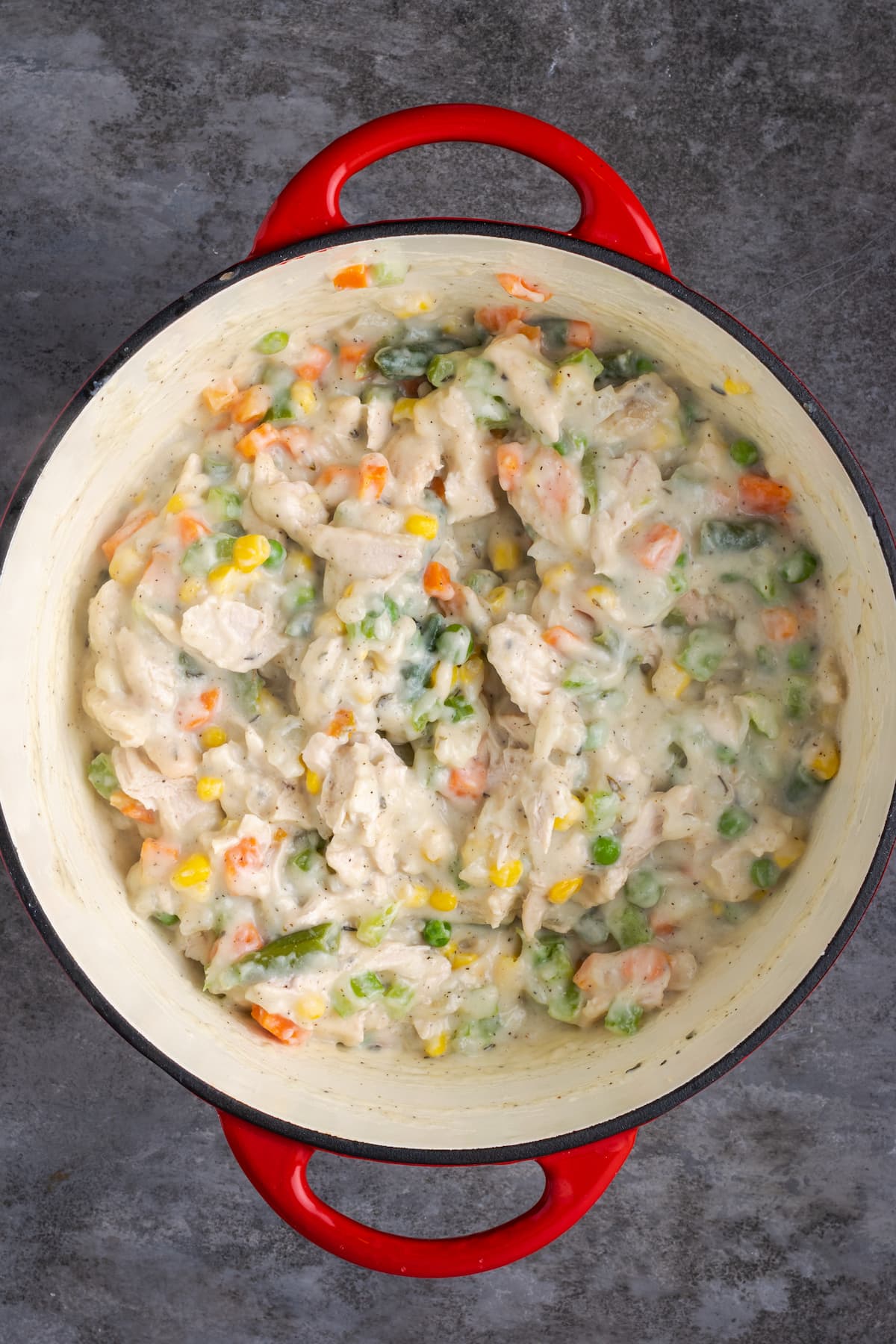 El Chicken Pot Pie casero es la mejor comida reconfortante, hecho con pollo cremoso y verduras horneadas dentro de una masa de pastel de hojaldre mantecosa. Relleno de pastel de pollo en una olla grande.