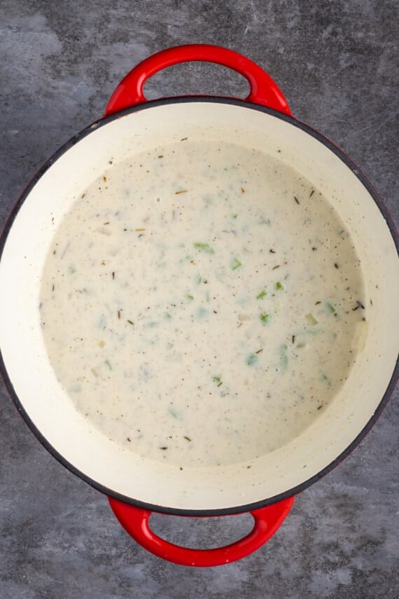 El Chicken Pot Pie casero es la mejor comida reconfortante, hecho con pollo cremoso y verduras horneadas dentro de una masa de pastel de hojaldre mantecosa. Leche y caldo agregados a la base para el relleno de pastel de pollo en una cacerola grande.