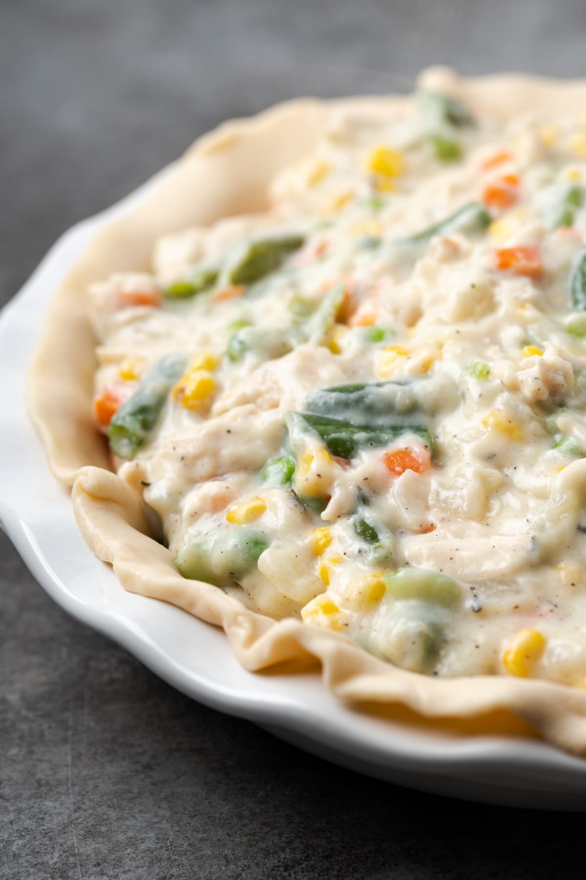El Chicken Pot Pie casero es la mejor comida reconfortante, hecho con pollo cremoso y verduras horneadas dentro de una masa de pastel de hojaldre mantecosa. Pastel de pollo relleno con una corteza escamosa dentro de un molde para pastel.
