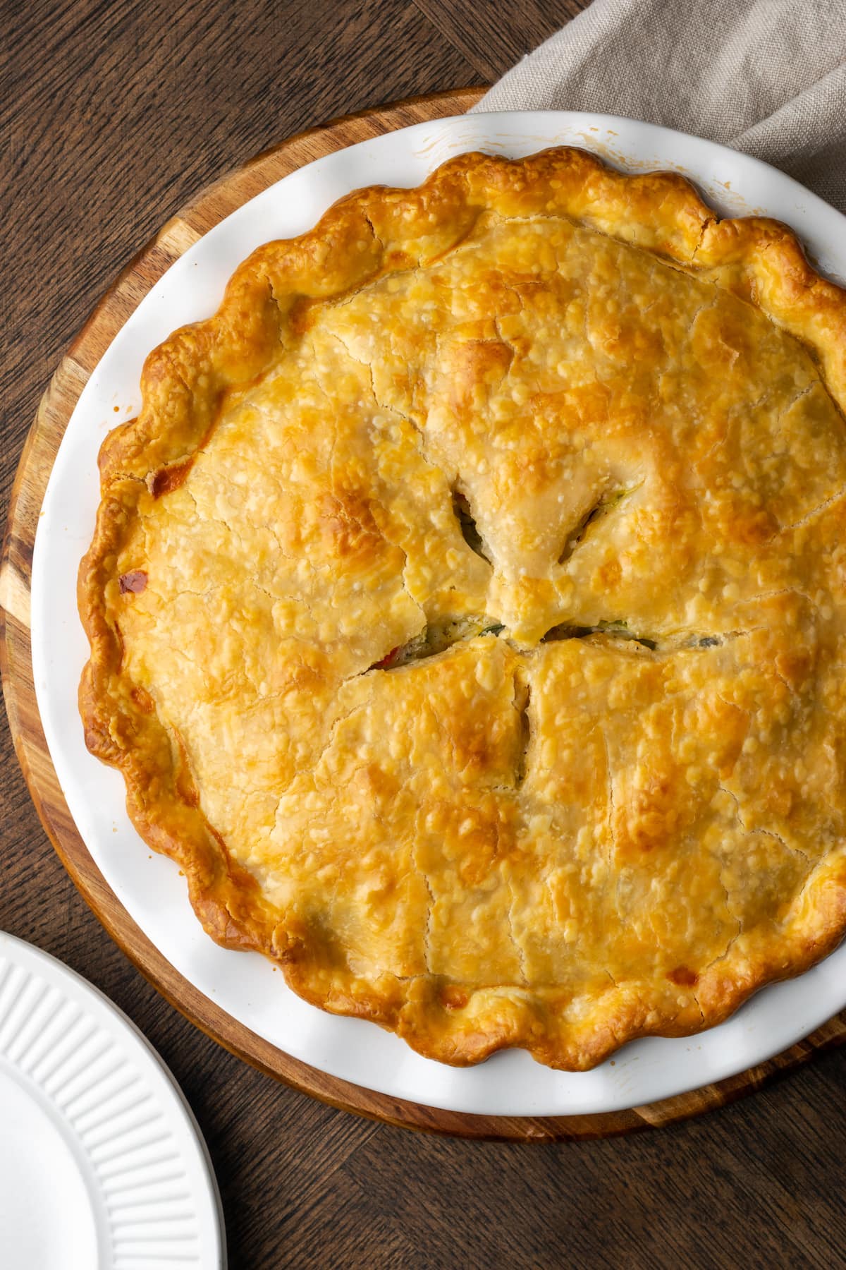 El Chicken Pot Pie casero es la mejor comida reconfortante, hecho con pollo cremoso y verduras horneadas dentro de una masa de pastel de hojaldre mantecosa. Vista aérea de pastel de pollo al horno en un plato de pastel.