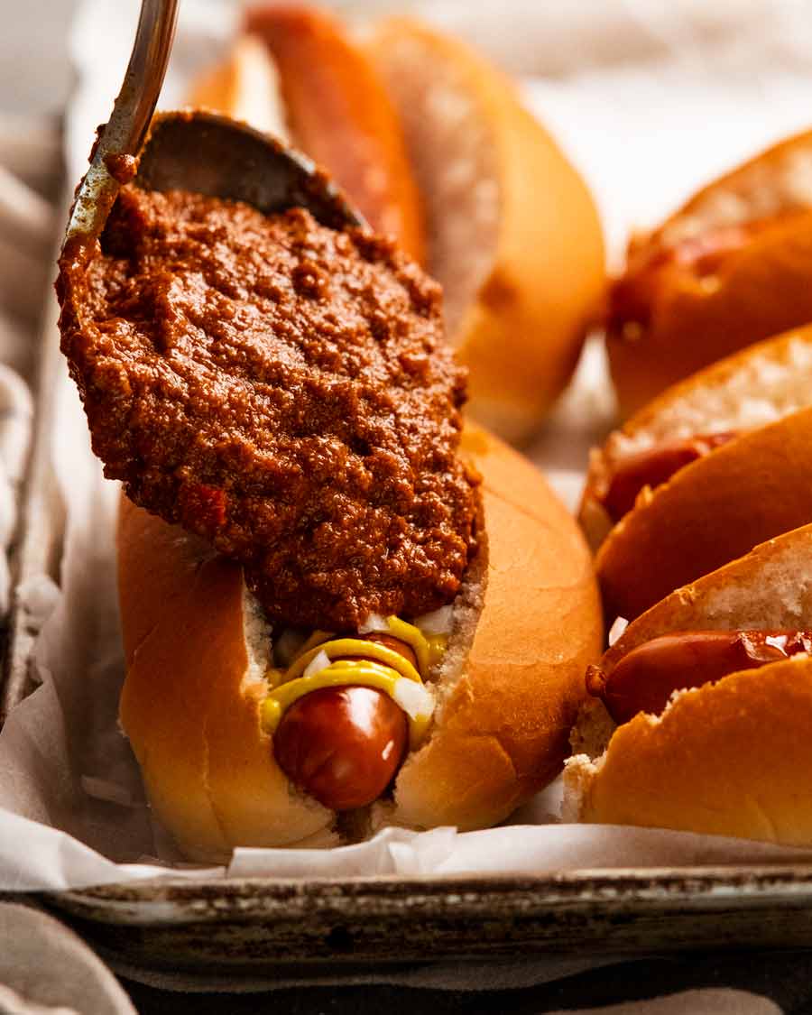 Sirviendo salsa de chili sobre chili dogs