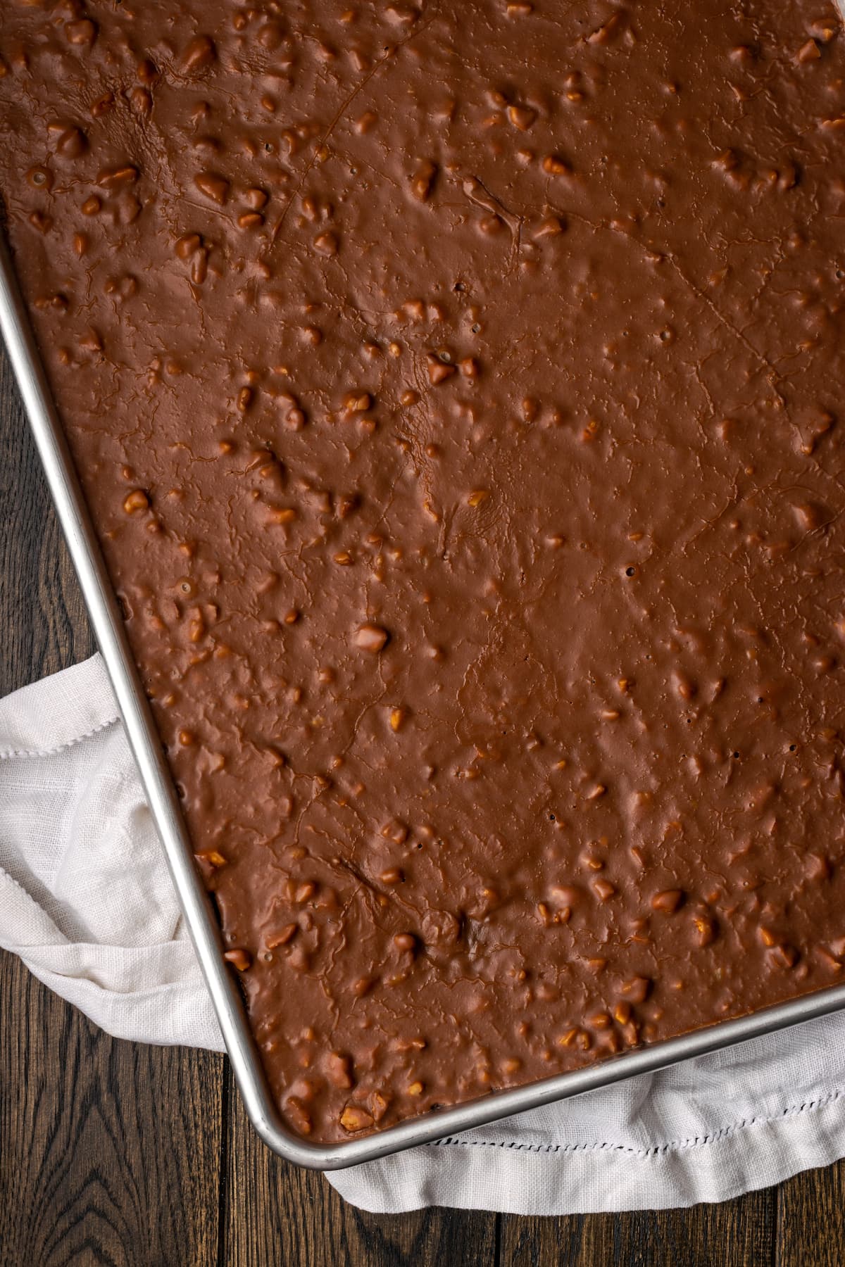 Fudgy Texas Sheet Cake es el sueño de los amantes de los pasteles de chocolate. Esta receta fácil de pastel está cubierta con glaseado de chocolate y es perfecta para fiestas. Vista aérea de un pastel de hoja de Texas cubierto con glaseado de nuez de chocolate.