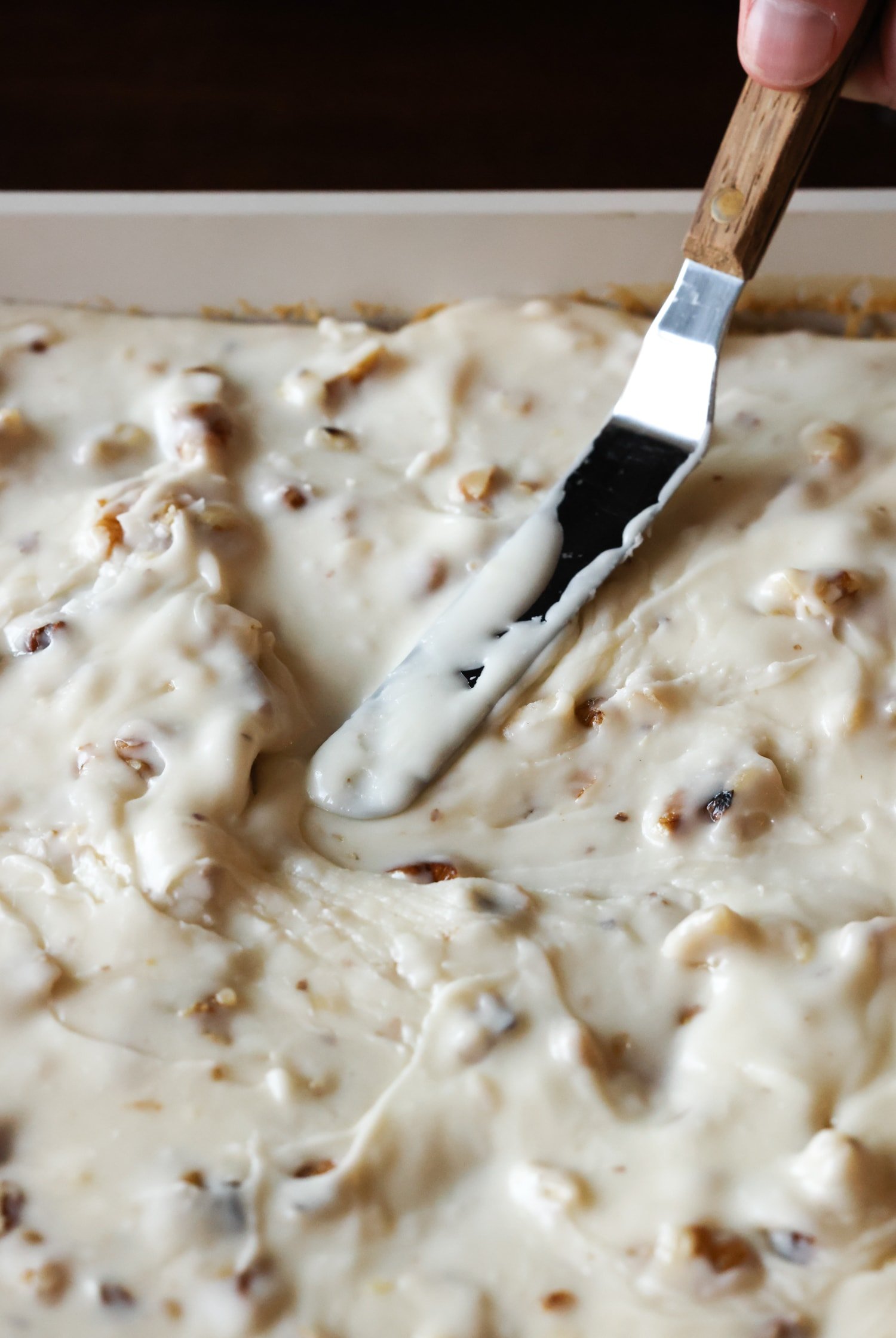 esparciendo glaseado de nuez en un pastel con una espátula desplazada