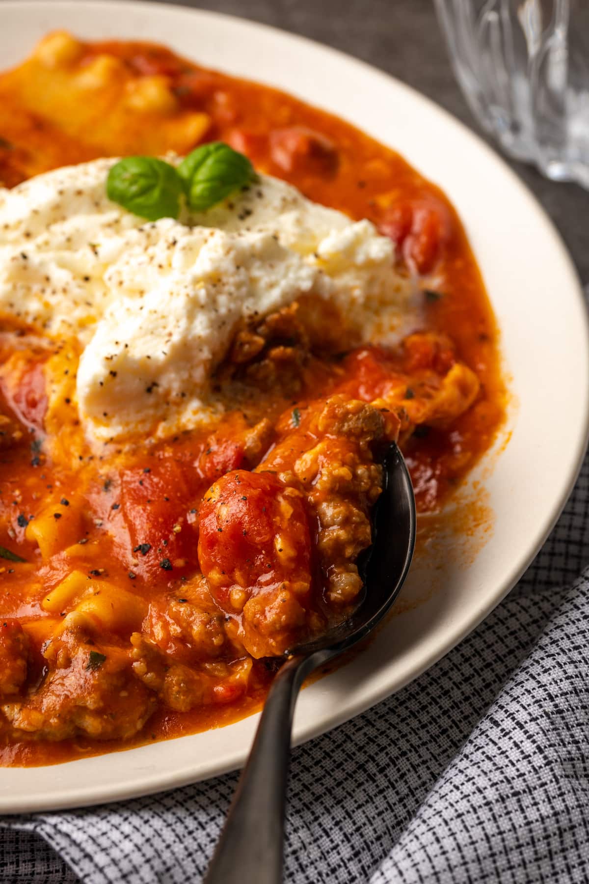 La sopa de lasaña es todo lo que amamos de lasaña casera envuelta en una comida de una sola olla. ¡Prepara esta receta fácil de sopa en 30 minutos o menos! Un tazón de sopa de lasaña cubierto con queso ricotta y hojas de albahaca.