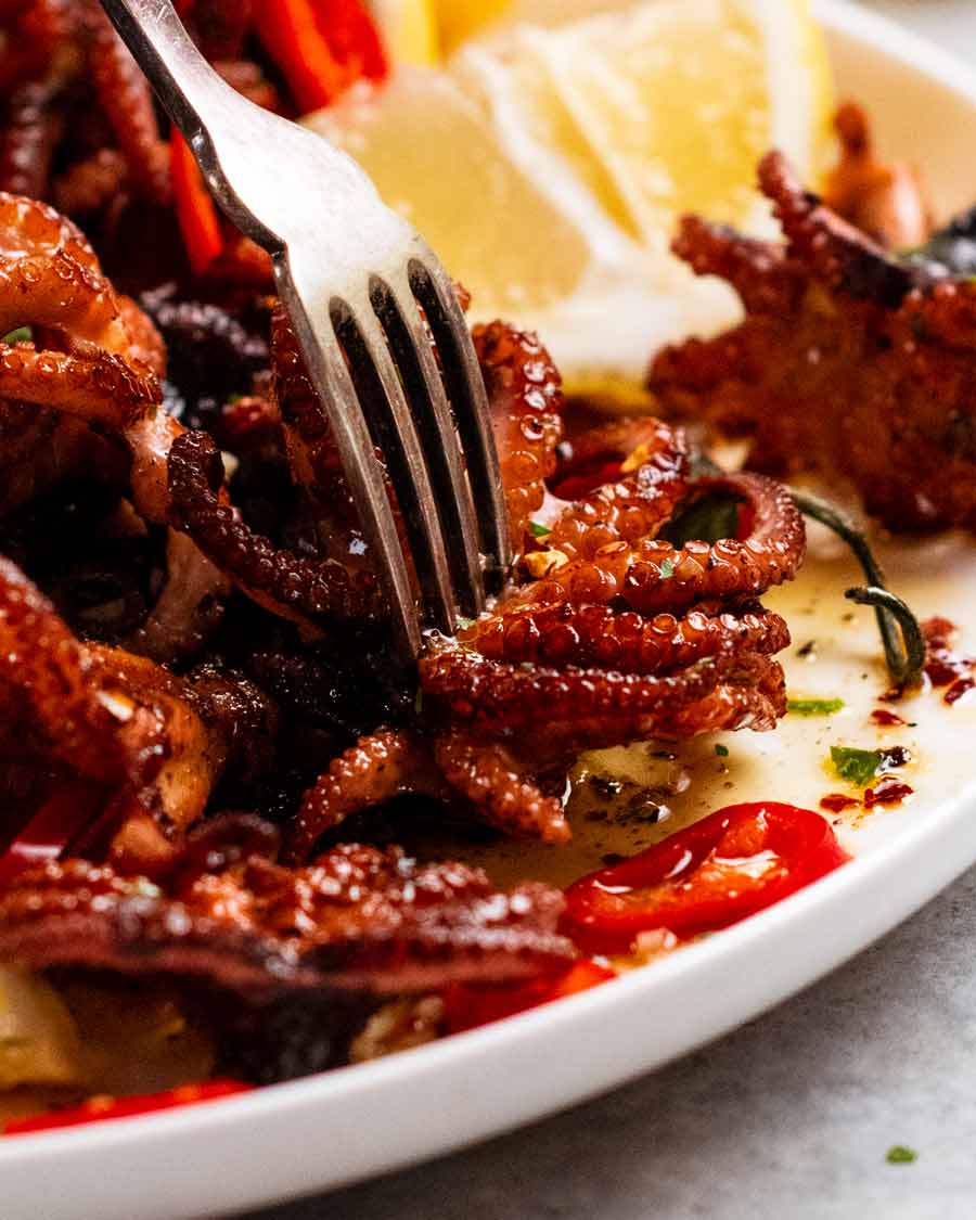 Tenedor recogiendo un trozo de pulpo bebé marinado Crispy