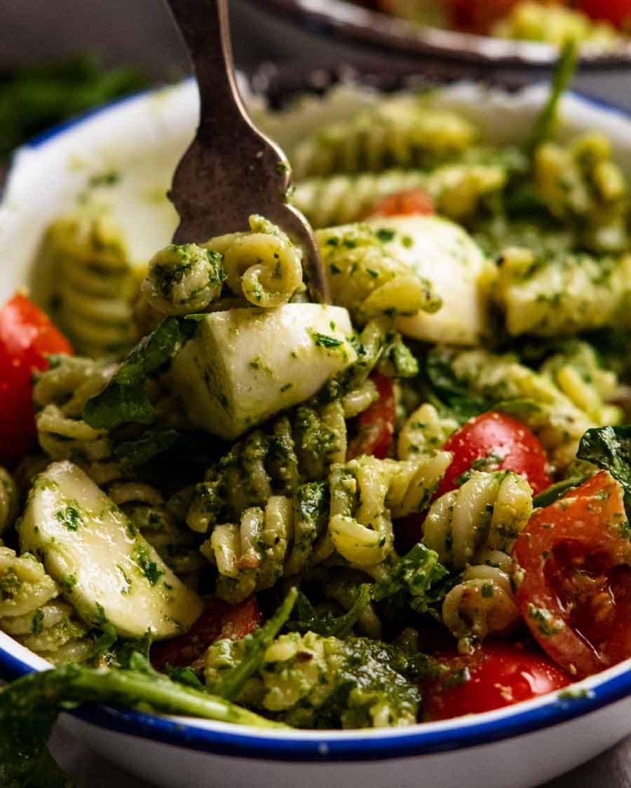 Primer plano de la horquilla recogiendo ensalada de pasta al pesto