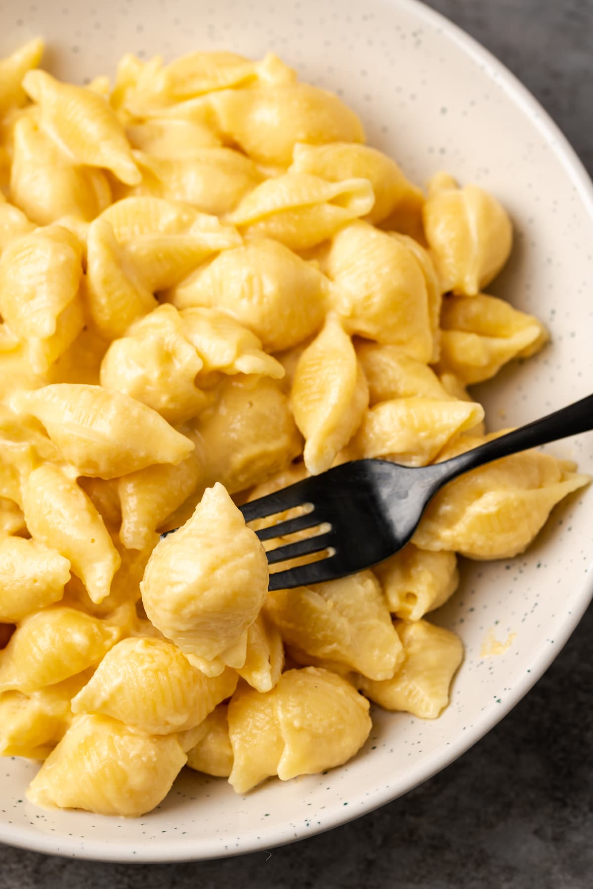 ¡Este Stovetop Mac and Cheese es un alimento reconfortante clásico, hecho en una olla con solo 5 ingredientes! Los macarrones con queso caseros nunca han sido tan fáciles. Un tenedor recogiendo un bocado de un cuenco lleno de macarrones con queso.