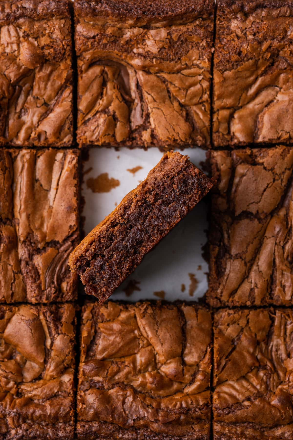 Los brownies caseros de Nutella son ricos, dulces y se arremolinan con crema de chocolate y avellanas. ¡Prepáralos en un tazón con solo 7 ingredientes! Vista desde arriba de brownies de Nutella cortados en cuadrados, con un brownie boca abajo.
