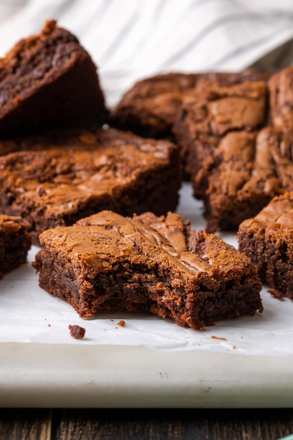 Los brownies caseros de Nutella son ricos, dulces y se arremolinan con crema de chocolate y avellanas. ¡Prepáralos en un tazón con solo 7 ingredientes! Brownies de Nutella en una tabla de cortar al que le falta un bocado en el brownie delantero.