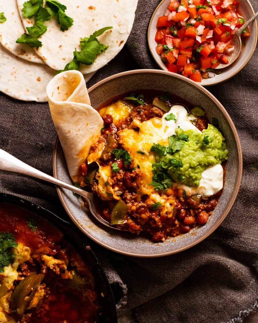 Fotografía aérea de una cazuela de frijoles y carne mexicana con queso y tortillas