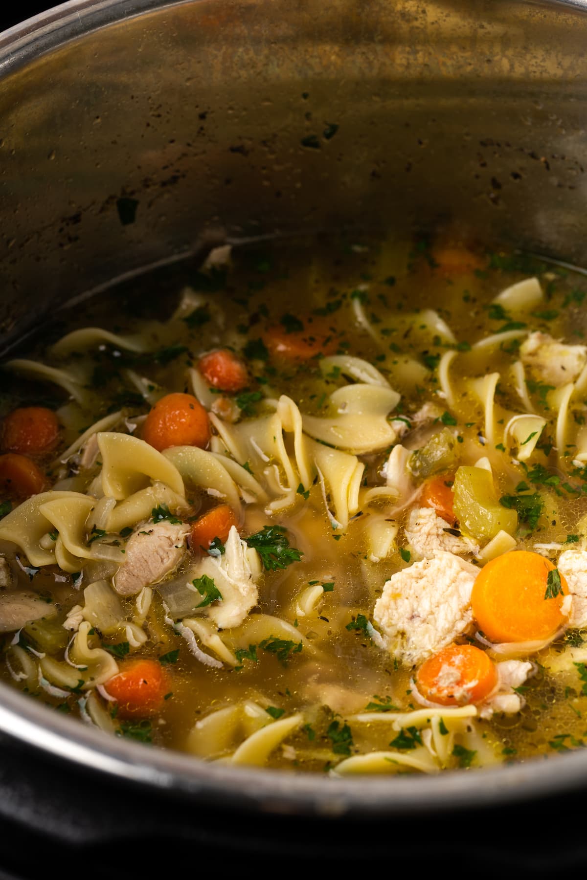 Instant Pot Chicken Noodle Soup es un atajo rápido y fácil para un alimento reconfortante favorito. Rebosante de ingredientes clásicos y toneladas de sabor. Primer plano de sopa de pollo con fideos dentro de Instant Pot.