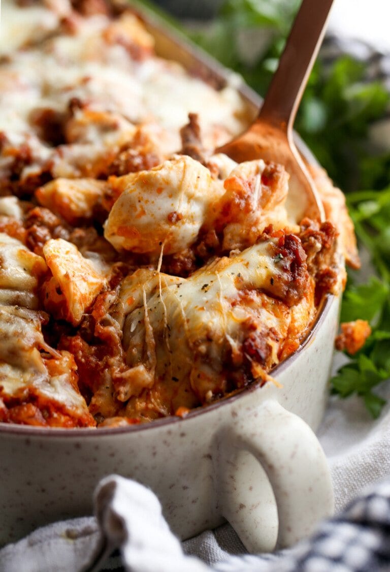 Cazuela de pasta de conchas sin relleno con una cuchara y queso derretido