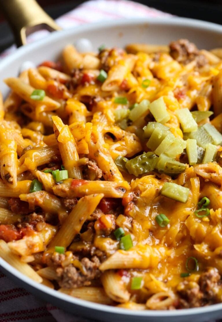 Pasta de hamburguesa con queso cubierta con queso, pepinillos y cebollas verdes