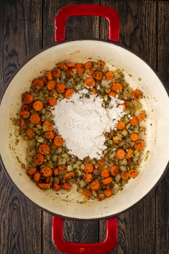 Harina añadida a las verduras salteadas en una olla grande.