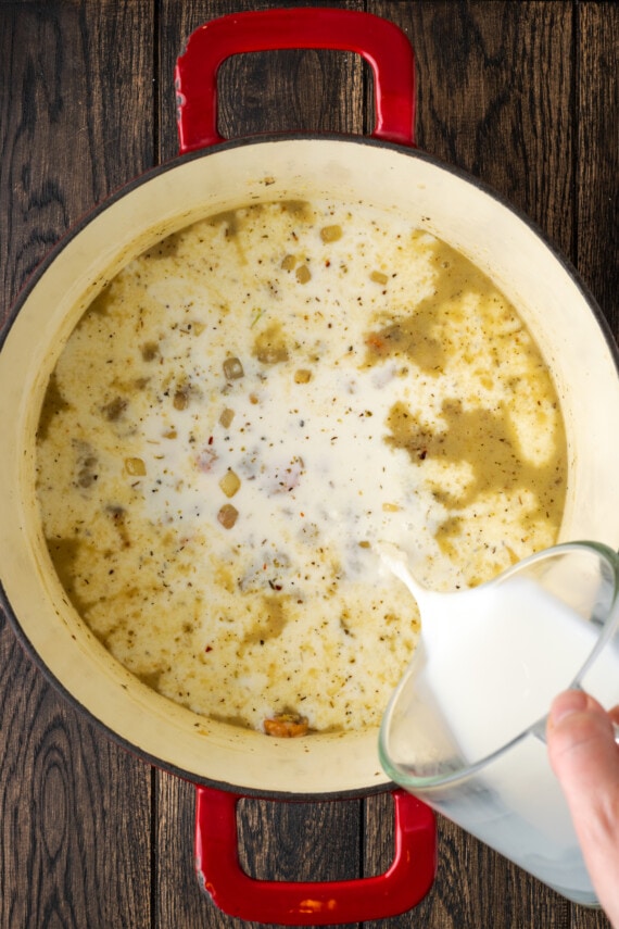 Leche vertida en una olla con verduras salteadas y caldo de pollo.