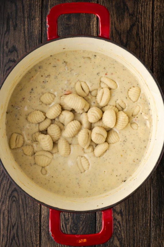 Ñoquis congelados agregados a una olla de sopa de pollo cremosa.