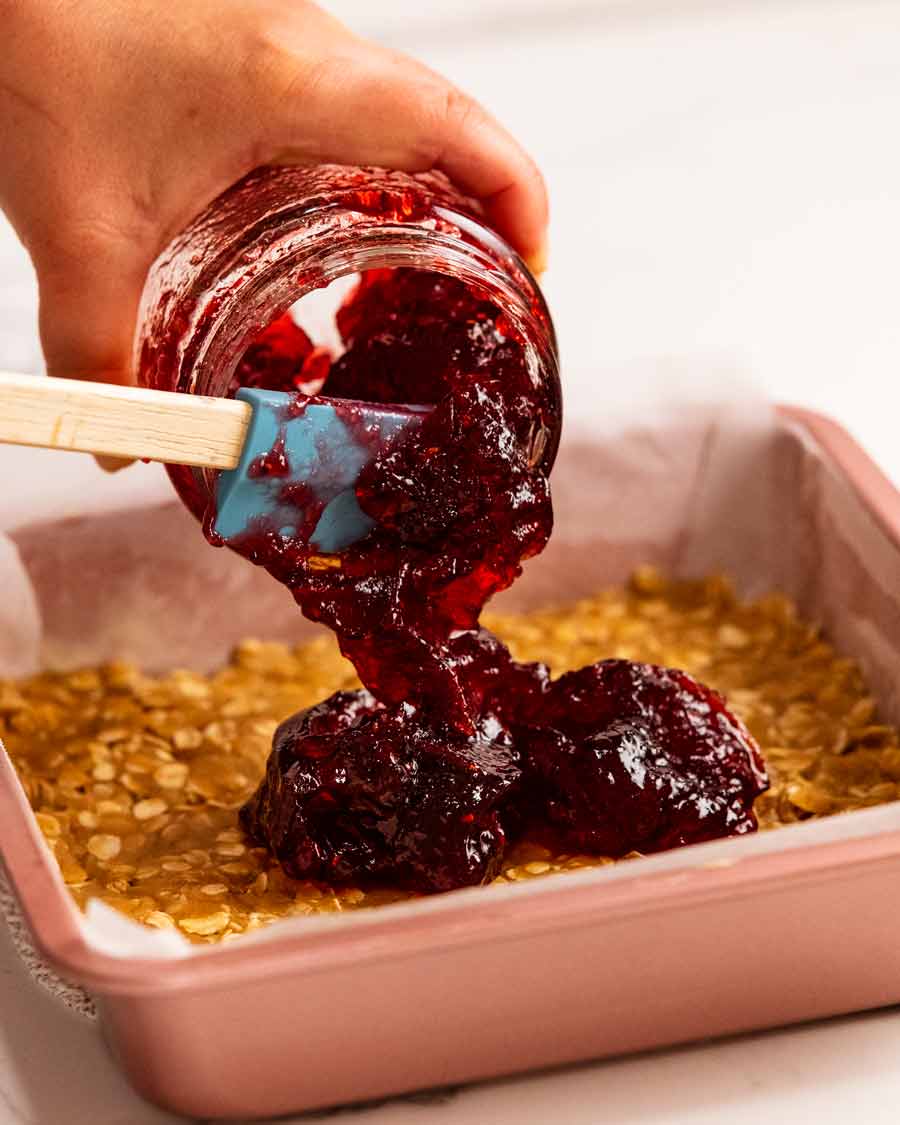 Verter mermelada en barras de avena con mermelada de frambuesa