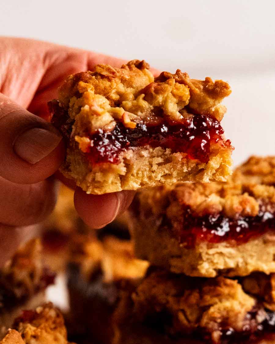 Mano sujetando la barra de avena con mermelada de frambuesa
