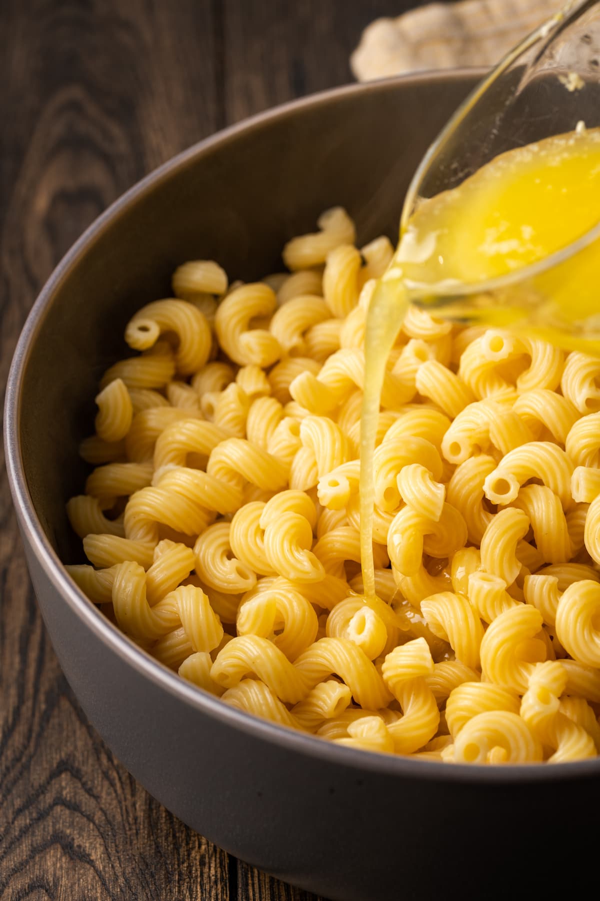La mantequilla de ajo derretida se vierte sobre la pasta cocida en una olla grande.
