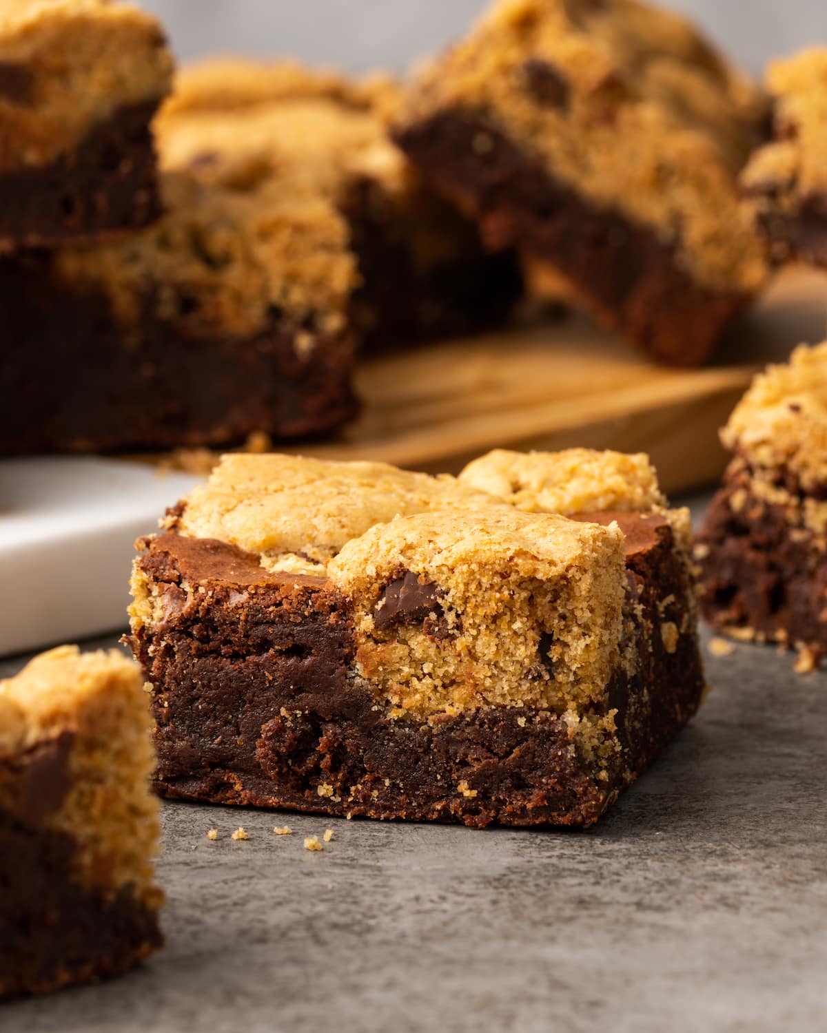 Esta receta fácil de brookies combina brownies de chocolate con galletas masticables con chispas de chocolate. ¡Las galletas de brownie con chocolate son lo mejor de ambos mundos! Una galleta de brownie en una encimera rodeada de más brookies en el fondo.