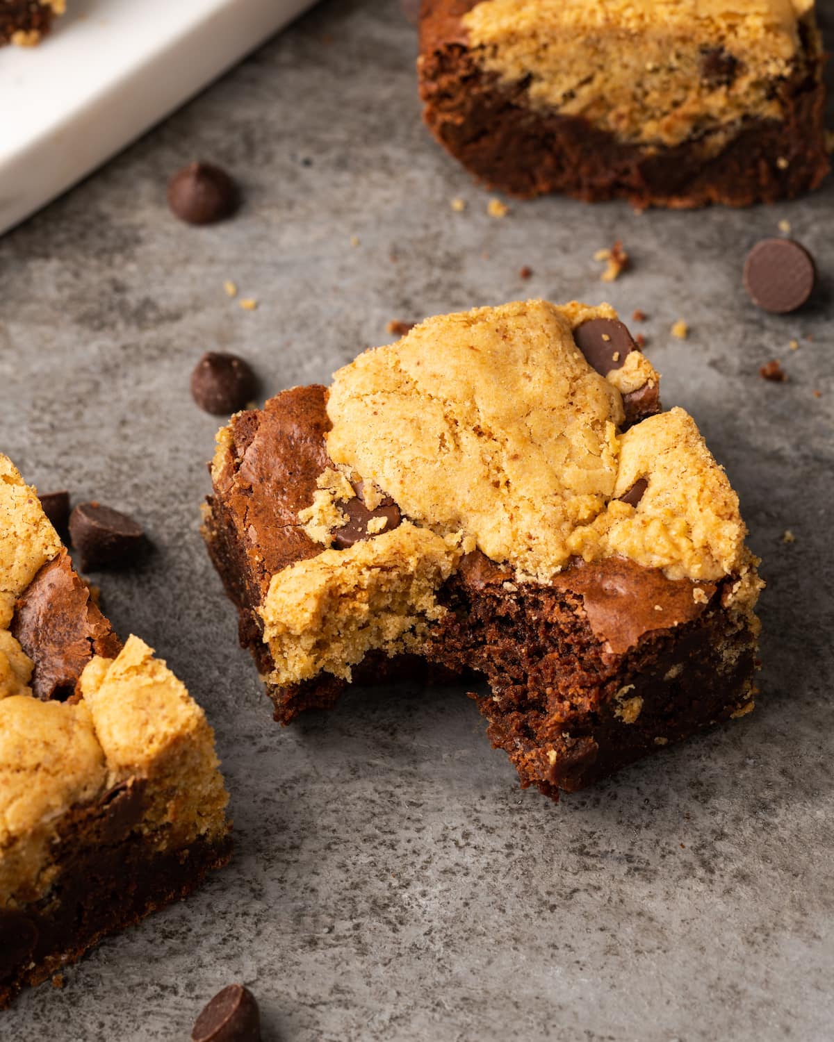 Esta receta fácil de brookies combina brownies de chocolate con galletas masticables con chispas de chocolate. ¡Las galletas de brownie con chocolate son lo mejor de ambos mundos! Vista aérea de un bar brookie casero al que le falta un bocado.