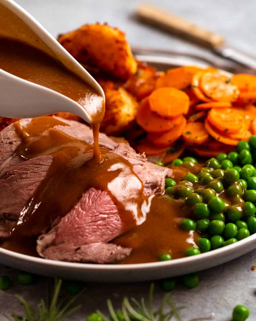 Verter salsa sobre pierna de cordero asado