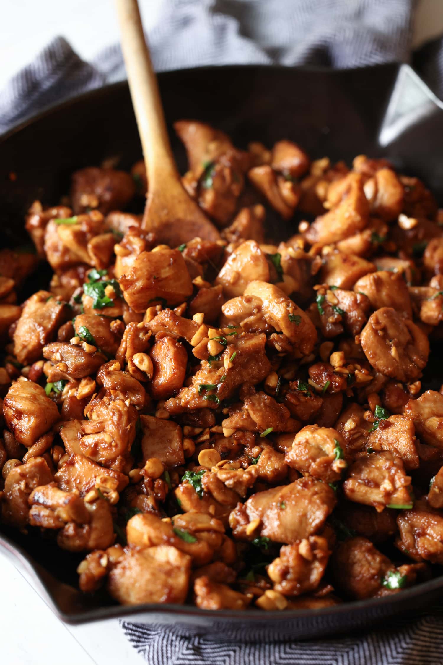 Este sencillo pollo al jengibre está cubierto con un dulce y pegajoso glaseado de soya y jengibre al estilo asiático salpicado de maní. ¡Listo en menos de 20 minutos! El pollo al jengibre se revuelve con una cuchara de madera mientras se cocina en una sartén de hierro fundido.
