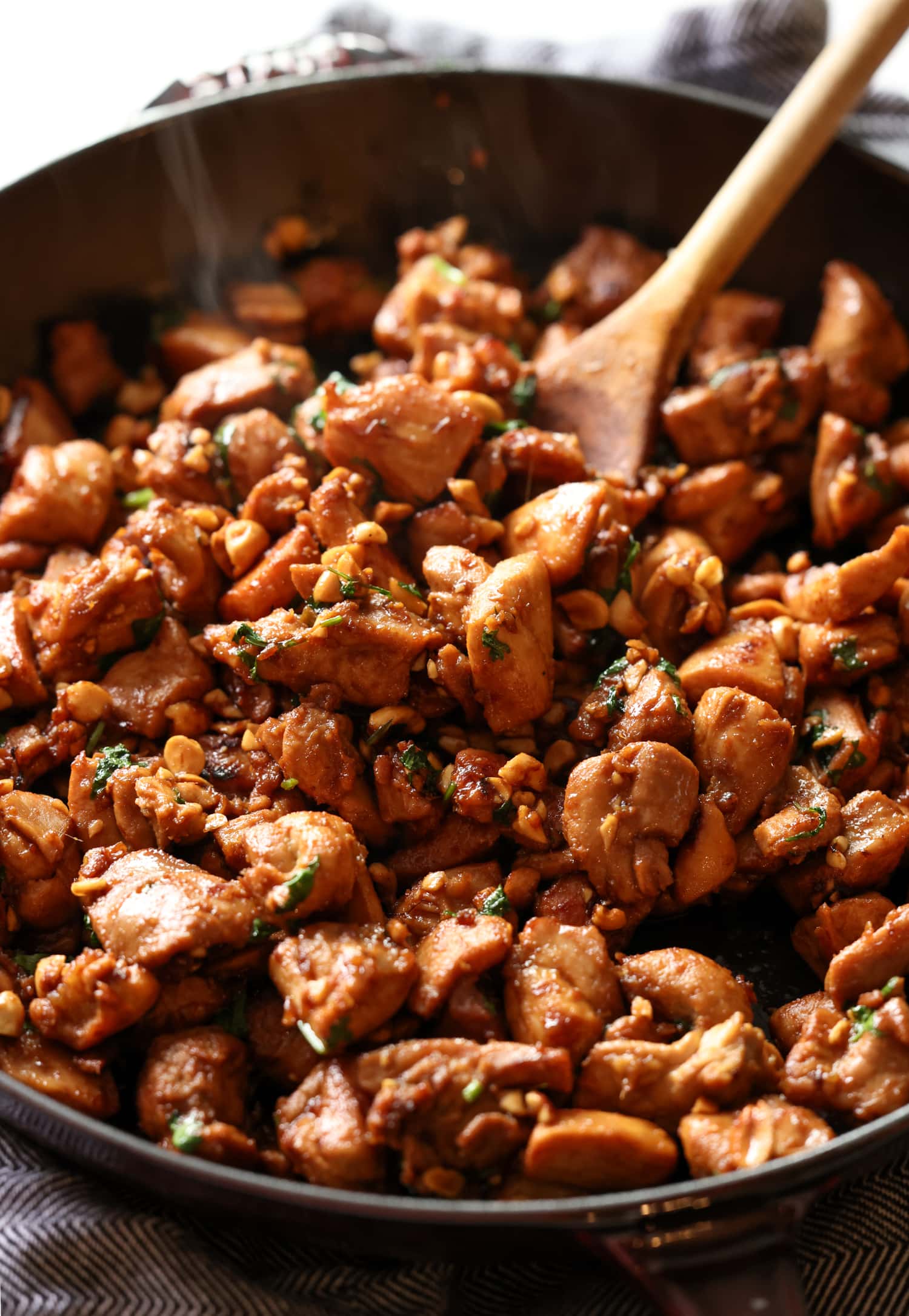 Este sencillo pollo al jengibre está cubierto con un dulce y pegajoso glaseado de soya y jengibre al estilo asiático salpicado de maní. ¡Listo en menos de 20 minutos! El pollo al jengibre se revuelve con una cuchara de madera mientras se cocina en una sartén de hierro fundido.