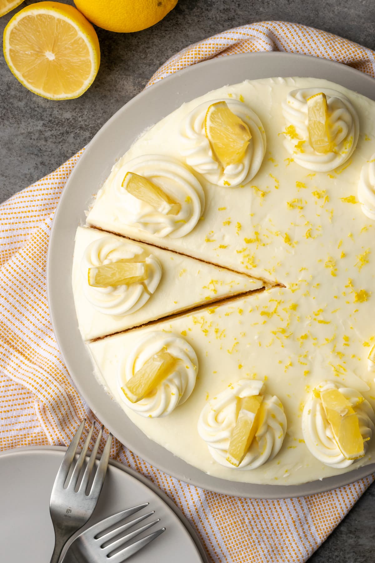 Los mejores postres de limón para darle un toque fresco a cualquier comida, desde sabrosas barras y pasteles de limón hasta postres sin hornear infundidos con cítricos soleados. Vista aérea del pastel de limonada cubierto con remolinos de glaseado y rodajas de limón, con una rodaja cortada.