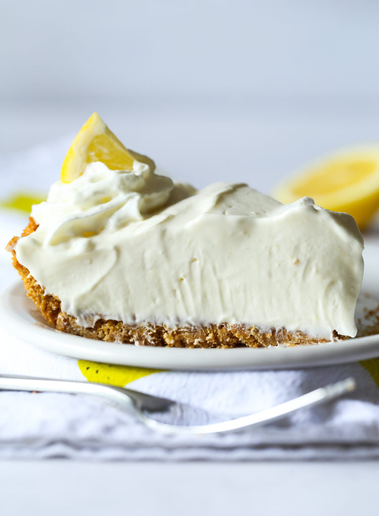 Un trozo de tarta de limonada en un plato con un tenedor en primer plano.