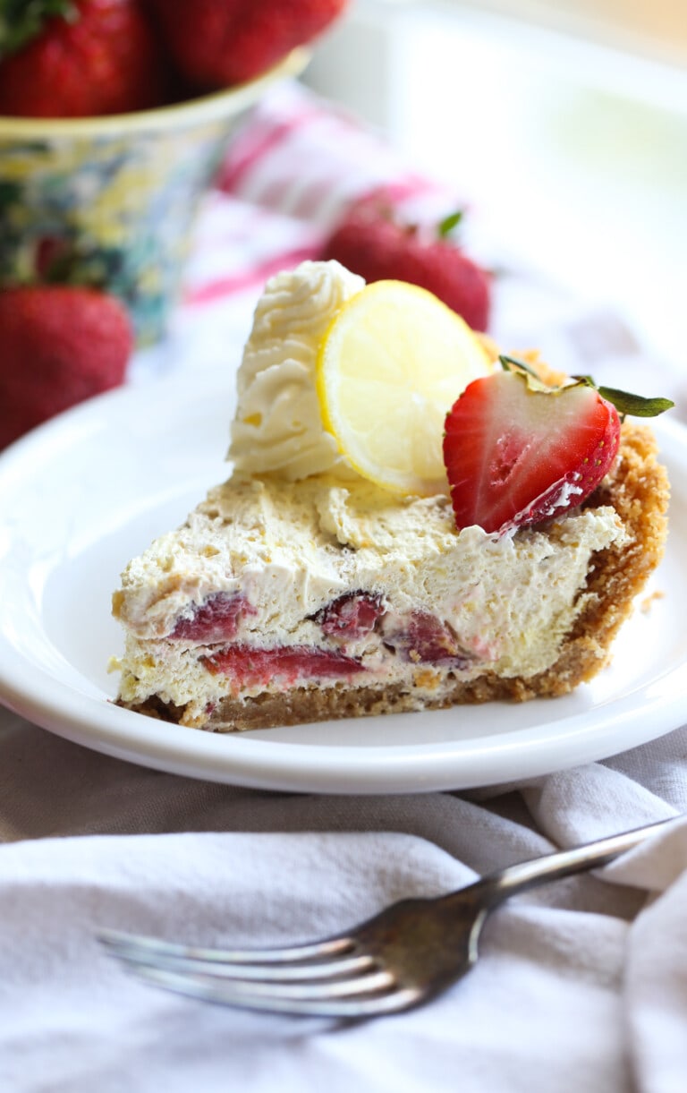 Rebanada de pastel de helado de limón y fresa sin hornear en un plato.