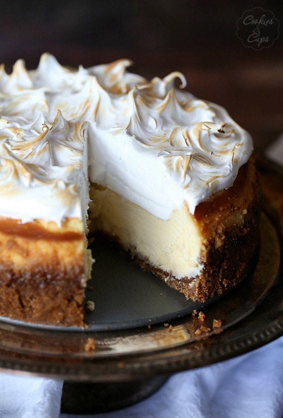 Tarta de queso con merengue de limón sobre un soporte para tartas a la que le falta una rebanada.