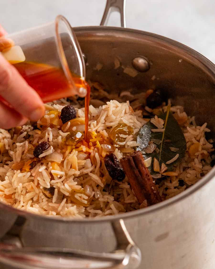 Verter agua de azafrán en el arroz pilaf enjoyado