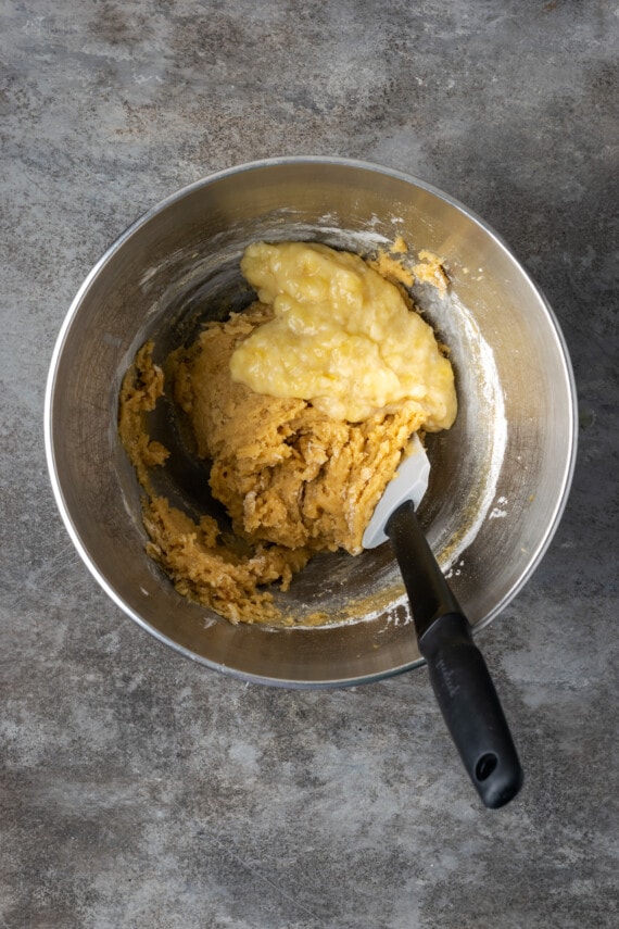 Banana Blondie Cheesecake es un postre fácil con cheesecake de vainilla al horno empapado en caramelo salado, en capas sobre una gruesa banana blondie. Puré de plátano agregado a la masa de blondie en un tazón para mezclar.