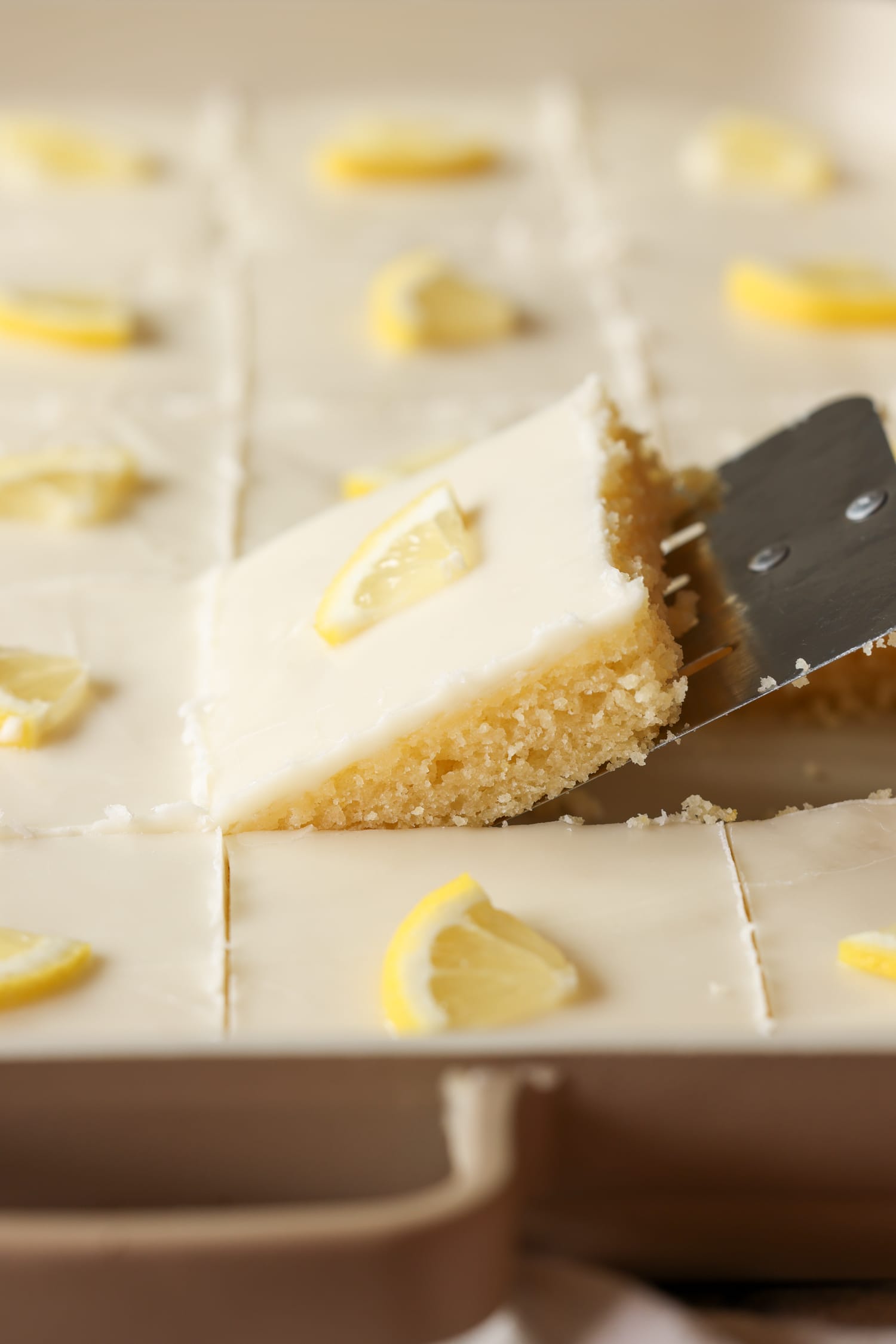 sacando un trozo de pastel de limón de la sartén con un servidor de pasteles