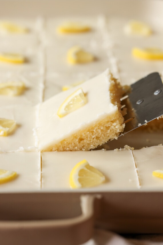 sacando un trozo de pastel de limón de la sartén con un servidor de pasteles